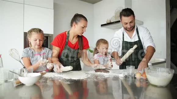 一起做饭他们在厨房里玩得很开心可爱的女儿和他们英俊的父母玩视频的预览图