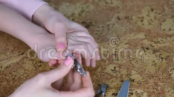 妈妈正在用剪刀在木头背上给儿子剪指甲双手合拢孩子的指甲视频的预览图