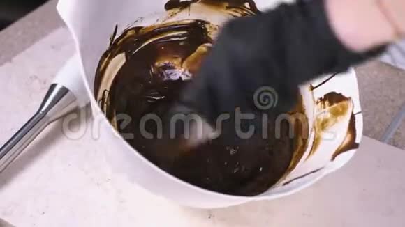 将液体黑巧克力与刮刀混合在白色碗中特写镜头视频的预览图