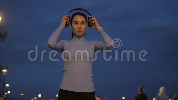 女孩戴上耳机在智能手表上播放音乐开始穿越夜城视频的预览图