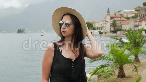 女孩坐在水边戴着草帽穿着黑色连衣裙视频的预览图