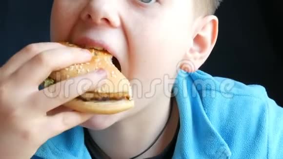 一个蓝眼睛的男孩在快餐店里轮流吃汉堡包和炸鸡翅视频的预览图