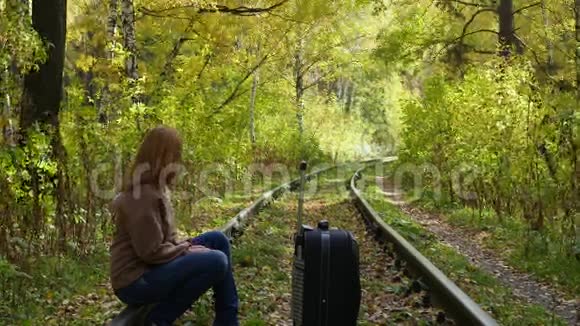 带着手提箱沿着铁路走的女孩视频的预览图