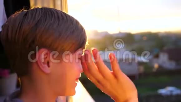 早上站在窗边的年轻人第一缕阳光照亮了房间他挥动他的手视频的预览图