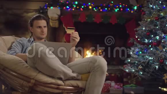 长发男子在圣诞夜使用笔记本电脑和信用卡在网上购物视频的预览图