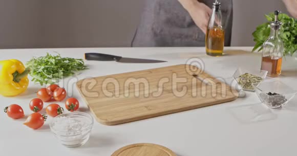 穿围裙的女人准备做蔬菜沙拉奶酪物种桌子上西红柿萝卜辣椒奶酪视频的预览图