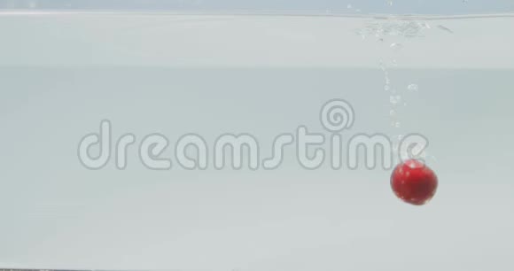 成熟的甜樱桃落在水中在一个干净的白色背景和飞溅水中的空气气泡慢慢视频的预览图