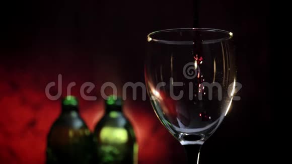 在玻璃杯中倒入红酒浪漫的气氛两瓶和深红色背景4k视频视频的预览图
