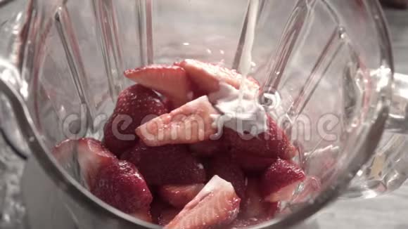 牛奶奶油溅入搅拌机的玻璃罐与红色成熟草莓水果上景全高清视频的预览图