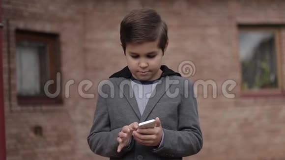 英俊的小男孩用他的手机壁砖的背景视频的预览图