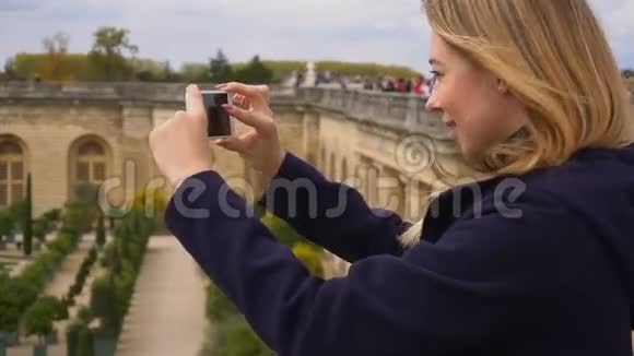 女游客用智能手机拍摄凡尔赛花园视频的预览图