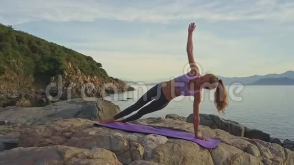 左臂上的苗条女孩平衡在岩石上的瑜伽姿势视频的预览图
