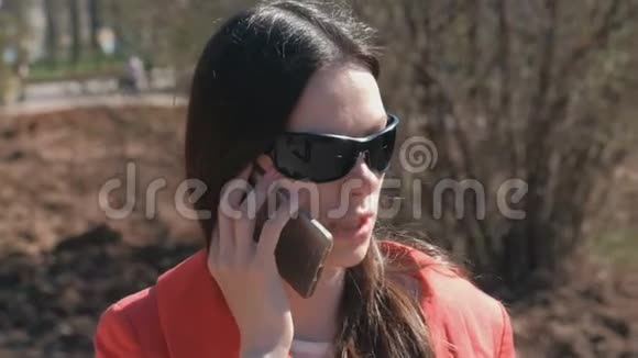 在春天公园里一位戴着太阳镜的黑发女青年正在打电话视频的预览图