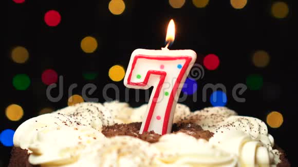 蛋糕上的7号7岁生日蜡烛燃烧在最后吹灭彩色模糊背景视频的预览图