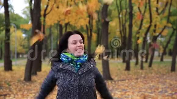 年轻女子在秋天公园里辗转落叶女戏树叶飘落全高清关闭视频的预览图
