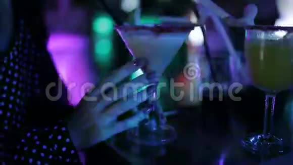 女孩在桌子旁跳舞喝着鸡尾酒酒吧柜台玻璃杯中的鸡尾酒特写视频的预览图