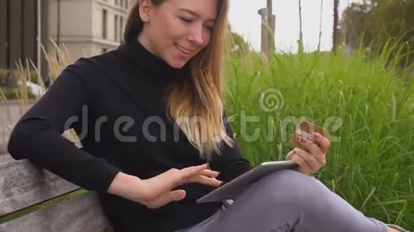 快乐的女人用笔记本电脑在公园里用金卡在线购物视频的预览图