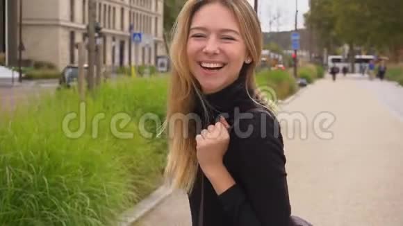 开朗的女孩走在路边微笑着看着相机吹着吻视频的预览图