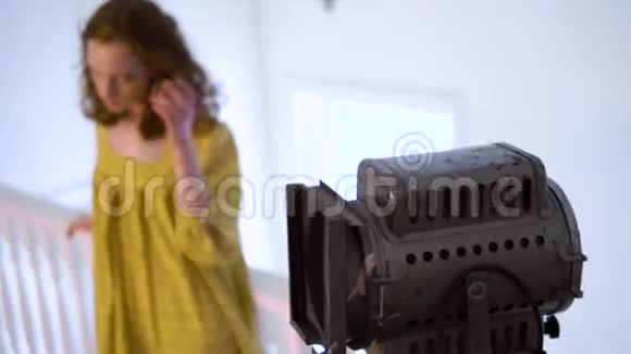 在摄影棚为照相机摆姿势穿黄色衣服的活泼开朗的女孩视频的预览图