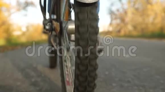 骑自行车在沥青路上女孩推自行车踏板的腿带踏车的车轮特写视频的预览图