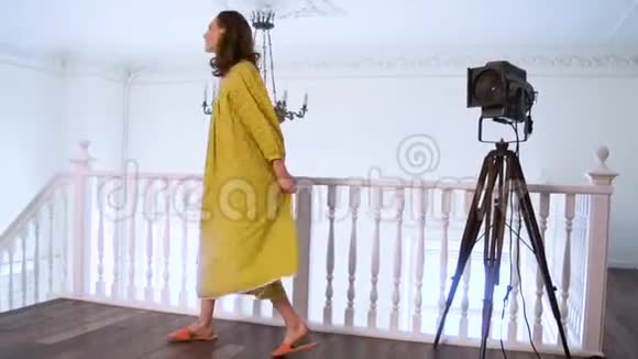 在摄影棚为照相机摆姿势穿黄色衣服的活泼开朗的女孩视频的预览图