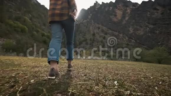 美丽的年轻女子旅行者在大自然中自由地穿越田野在群山把帽子扔到空中视频的预览图