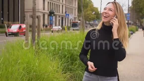 漂亮的女人用智能手机说话走在路边视频的预览图