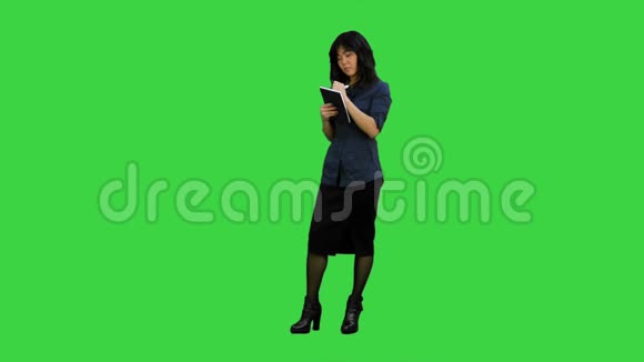 带背包的年轻亚洲女人有个主意在绿色屏幕上拿着笔记本Chroma键视频的预览图
