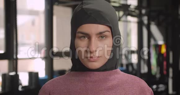 年轻迷人的穆斯林运动女性在室内健身房观看摄像机的特写照片视频的预览图