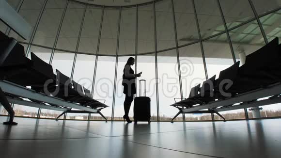 机场的女商人一个女孩的剪影有手机和行李手提箱平板电脑商业和视频的预览图