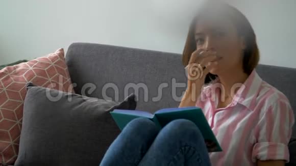 美丽的白人女孩手里拿着一本书坐在沙发上美丽迷人的白人女孩坐在沙发上拿着一个记事本视频的预览图