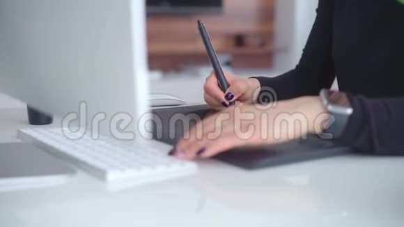 年轻女性使用图形平板电脑和手写笔在现代电脑屏幕后面工作视频的预览图