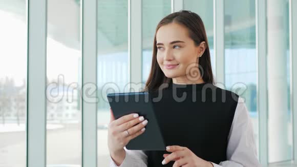 成功的女商人在办公室里用平板电脑女商人在窗口附近营业开心地微笑着机场视频的预览图