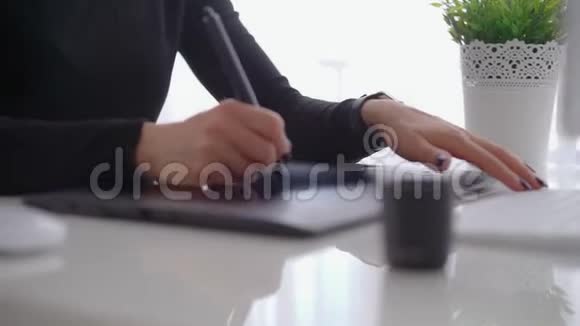 年轻女性使用图形平板电脑和手写笔在现代电脑屏幕后面工作视频的预览图
