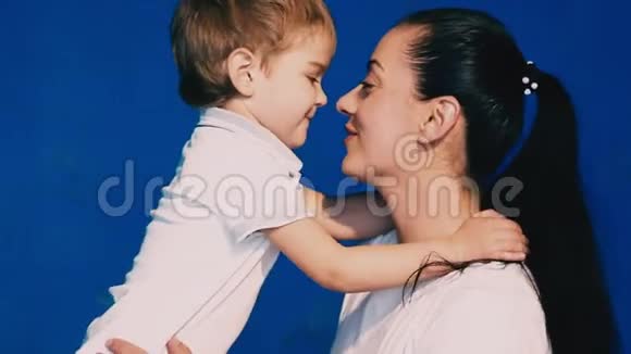 母亲和儿子在蓝色背景上玩笑和亲吻视频的预览图