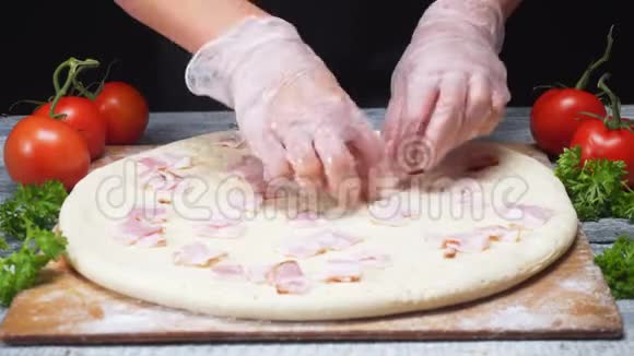 在保护手套中为厨师做意大利披萨并在披萨面团上加入火腿或培根视频的预览图
