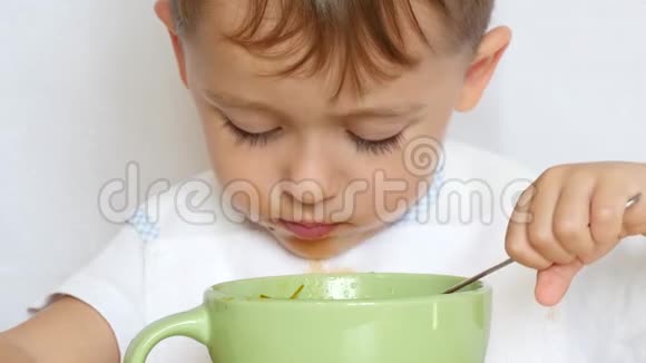 小孩用盘子里的勺子吃食物特写视频的预览图
