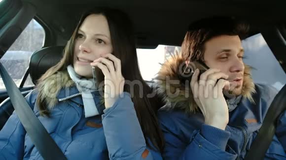 快乐的男人和女人说他们的手机坐在车里前景视频的预览图