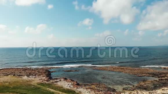 蓝色风景秀丽的大海和岩石海岸线的鸟瞰强烈的溅起泡沫视频的预览图