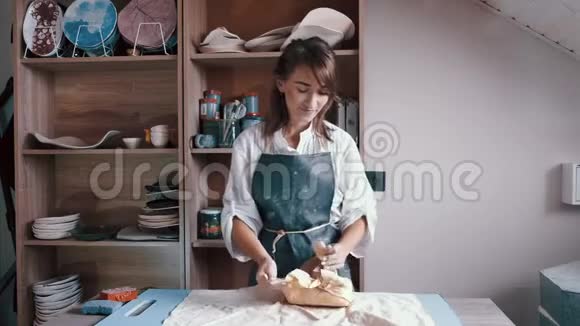 一个穿围裙的女陶工准备和滚泥视频的预览图