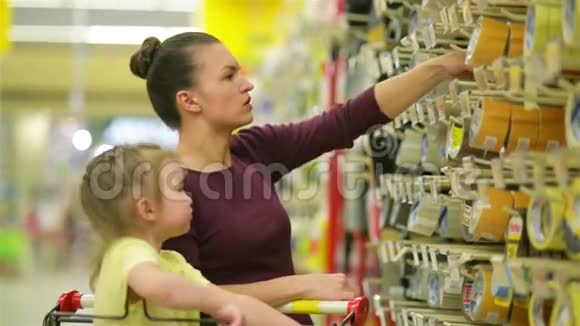 在超市里微笑的母女一个女儿帮助她的母亲选择胶带可爱的女儿视频的预览图