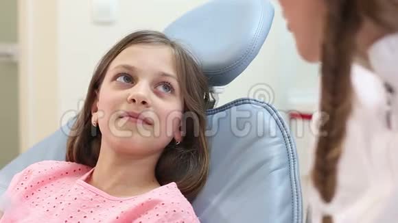 合上坐在牙科椅上听牙医讲话的可爱女孩视频的预览图
