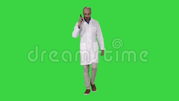 专业医生在绿色屏幕上行走时用手机交谈Chroma键视频的预览图