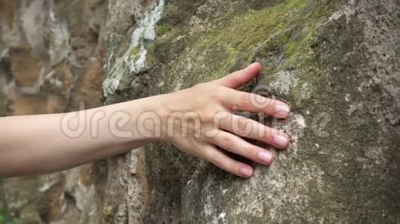 女人慢慢地用手拉着旧石墙女性触摸粗糙的岩石表面视频的预览图