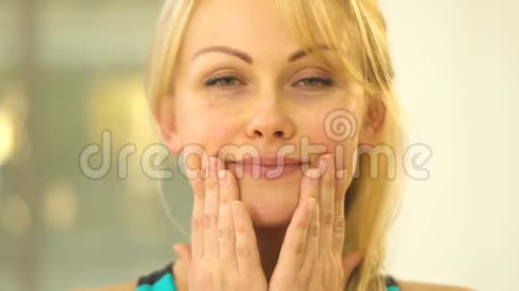 金发美女表现出脸部训练双手握着嘴吹着唇下的空气视频的预览图