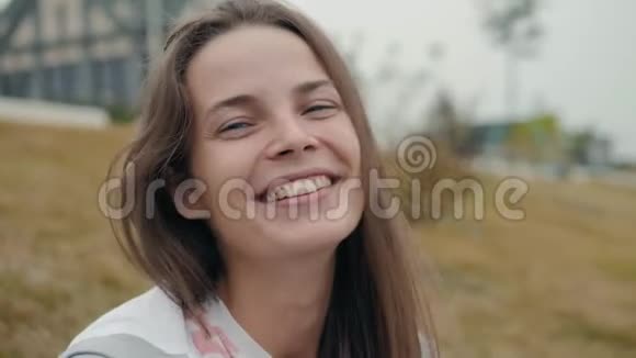 幸福的女人带着完美的微笑看着户外的摄像机在街头学生快乐的笑着微笑着年轻的视频的预览图