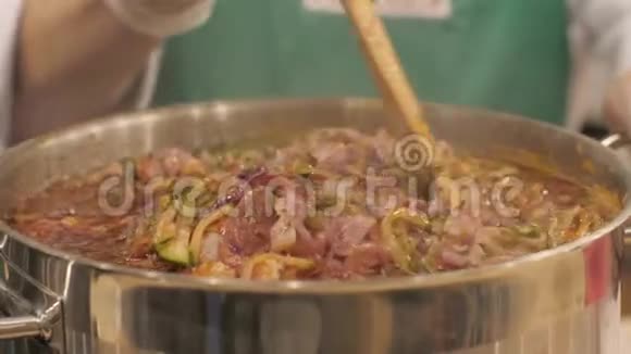 厨师在锅中煮肉汤时在厨房里把肉汤搅在一起视频的预览图
