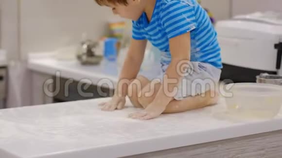 有趣的男孩在厨房里玩面粉家里麻烦的孩子淘气的孩子视频的预览图
