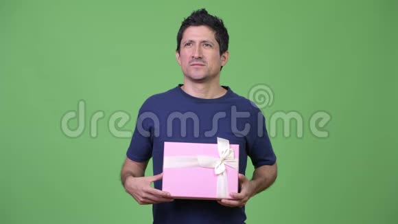 快乐的西班牙男人一边想一边拿着礼品盒视频的预览图