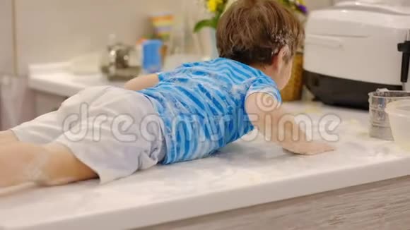 有趣的男孩在厨房里玩面粉家里麻烦的孩子淘气的孩子视频的预览图